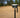 A GNSS antenna attached to a GNSS receiver standing on a pole with a sandy background and palm threes behind.