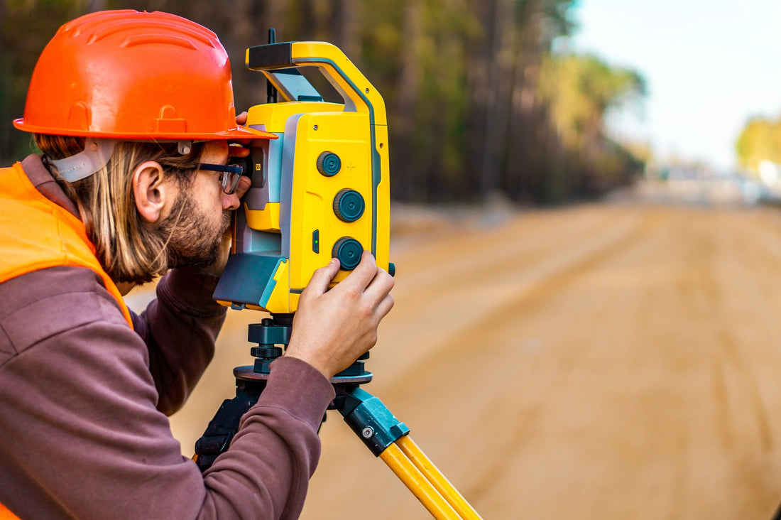 A surveyor using a total station and a prism pole to conduct a survey 