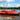 Red autonomous USV survey boat equipped with GNSS antennas on a modern gradient background for hydrographic and geodetic mapping