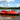 Red autonomous USV survey boat equipped with GNSS antennas on a modern gradient background for hydrographic and geodetic mapping