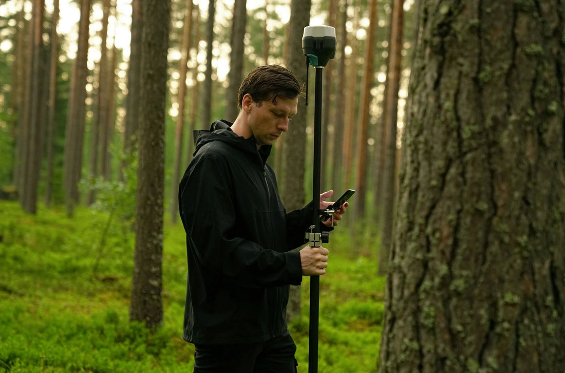 GNSS accessories and land surveying equipment positioned in a green field with buildings shown in the background. 