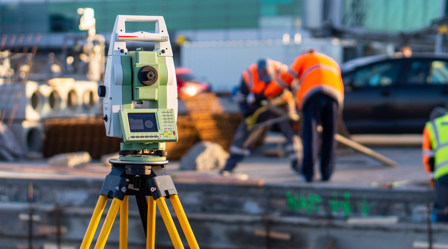 The Leica TRC1201+ total station is positioned on a tripod at the construction site.